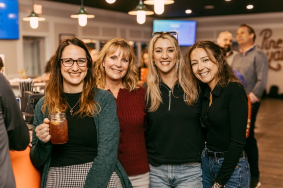 Four friends smiling together inside the Pine Royale bar and restaurant
