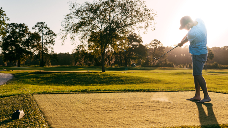 A golfer teeing off at sunset on the par 3 course at Pine Royale