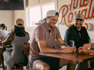 Two friends laughing over drinks at a table in the Pine Royale dining room