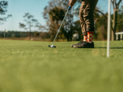 A golfer in checkered socks lining up a putt toward the cup