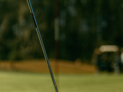A putter set behind the ball on the green, the flag blurred beyond