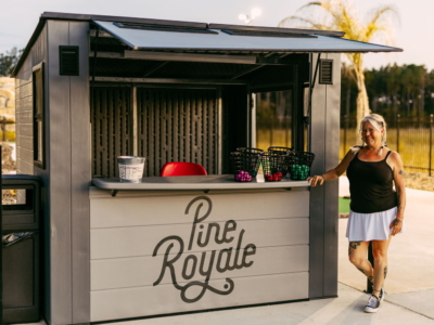An attendant beside the Pine Royale starter hut at Mini Royale, baskets of balls on the counter