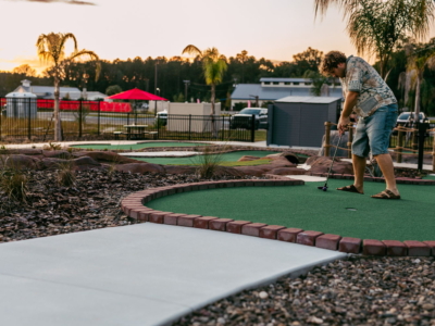 A man in a floral shirt putting on a brick-edged Mini Royale hole at sunset