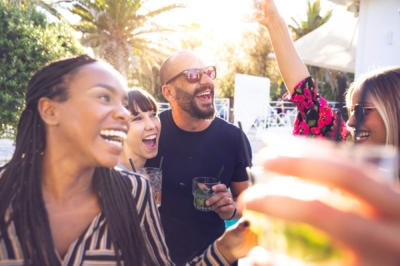 Friends laughing and raising their drinks on a sunny patio