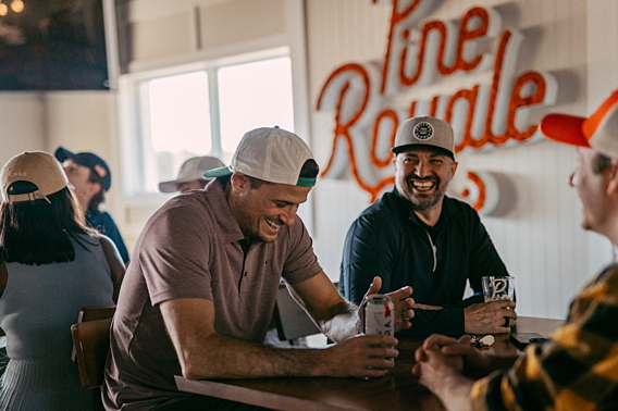 Two guests laughing over drinks at a table in the Pine Royale bar