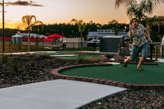 A player celebrating a putt on a Mini Royale hole at sunset