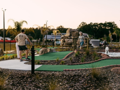 Players on the newly opened Mini Royale course at sunset, the rock waterfall behind